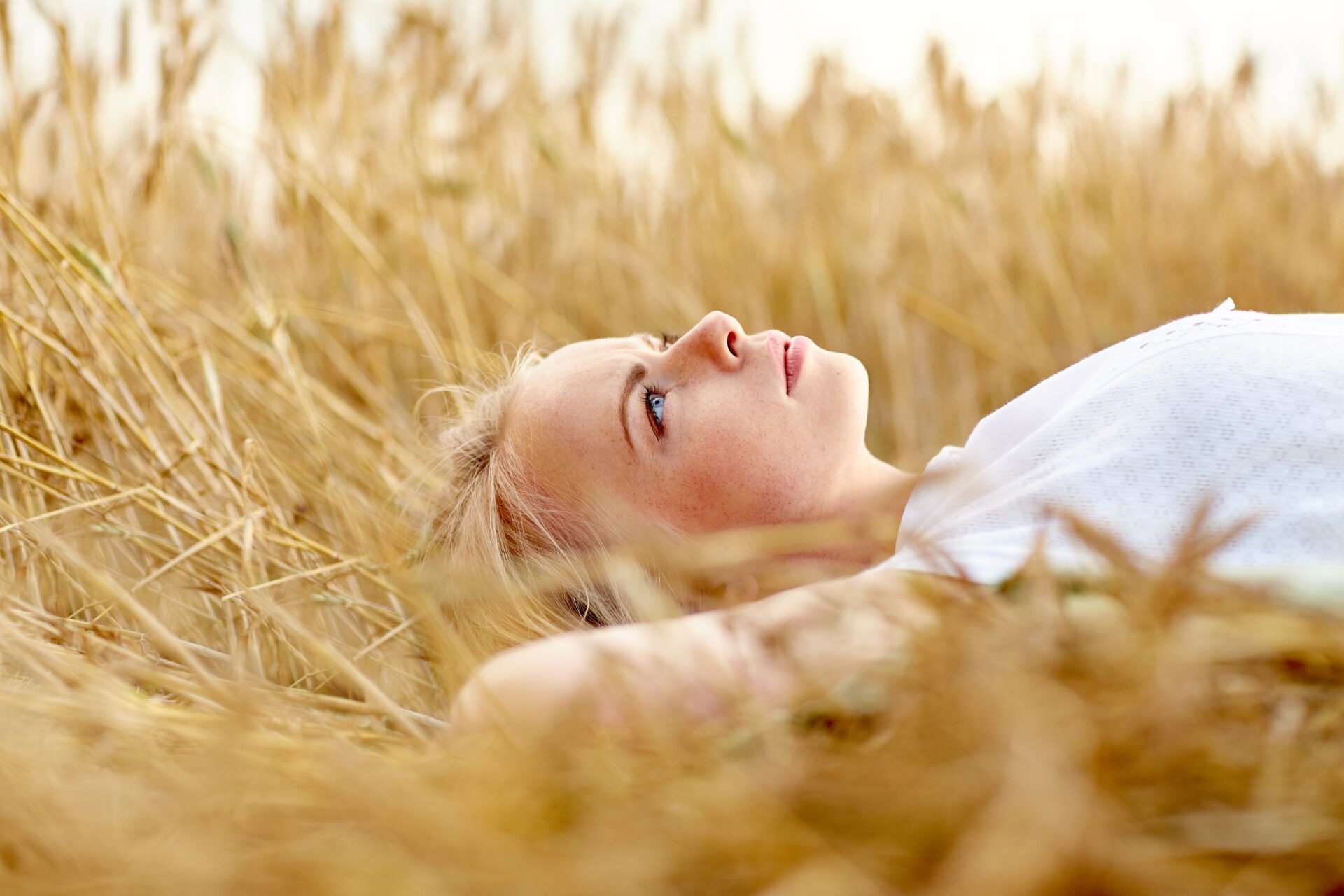 Hyväntekeväisyyskö itsekästä? artikkelin pääkuva, jossa nainen makaa viljapellolla pohdiskelevan näköisenä.